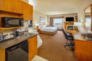 a hotel room with a kitchen and a bedroom at Clarion Pointe in Rimbey
