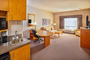 a hotel room with a kitchen and a living room at Clarion Pointe in Rimbey