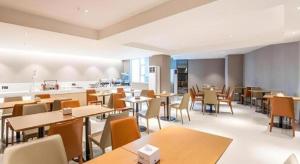 ein Restaurant mit Tischen und Stühlen und einer Küche in der Unterkunft City Comfort Inn Nanning Railway Station Guangxi University in Nanning