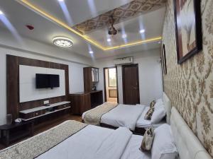 a hotel room with two beds and a flat screen tv at Hotel The Sankalp Retreat in Bhavnagar