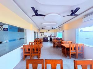 a dining room with wooden tables and chairs at ফোর স্কয়ার Four Square Lite Heaven Digha Near The Sea Beach in Digha