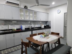 Warisan Iman Inn في كلانغ: مطبخ مع طاولة خشبية مع كراسي وكاونتر