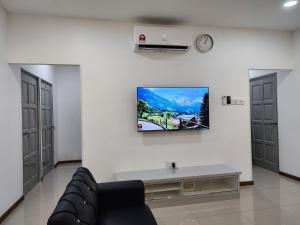 Warisan Iman Inn في كلانغ: غرفة معيشة مع أريكة وتلفزيون على الحائط