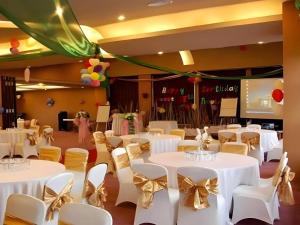LampungHotel Grand Anugerah的宴会厅里摆放着白色桌子和金色蝴蝶结