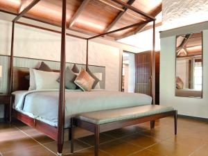 ChillithoduAelam Acres的一间卧室配有天蓬床和长凳