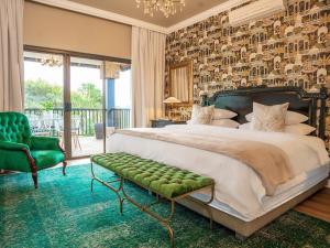 a bedroom with a large bed and a green chair at The First House Luxury Villa, Eden Rock Estate in Pennington