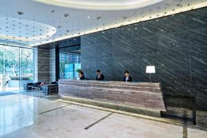 Hotel COZi·Wetland في هونغ كونغ: ثلاثة أشخاص يجلسون في كونتر في بهو الفندق