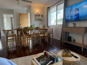 sala de estar con mesa de comedor y TV en Chic Urban Escape in Norman Park, en Brisbane 23 fotos más