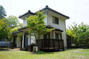 a house with a tree in front of it at Private stay MIYAJIMA tonbo-AND in Hatsukaichi