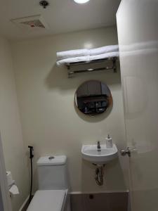 ein Badezimmer mit Toilette, Waschbecken und Spiegel in der Unterkunft Rent & Roam in Baguio City + 5 Fotos