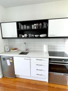 kuchnia z białymi szafkami i zlewem w obiekcie Heritage studio with private balcony w Auckland