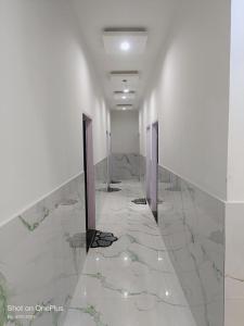 a hallway with white walls and marble floors at Om Baikunth Dham in Vrindāvan