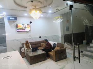 two men sitting on a couch in a room at Om Baikunth Dham in Vrindāvan