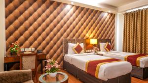 新德里阿尔皮娜酒店&套房的一间卧室设有两张床和一个大垫墙