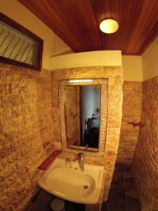 Lumbalumba Resort - Manado في مانادو: حمام مع حوض ومرآة