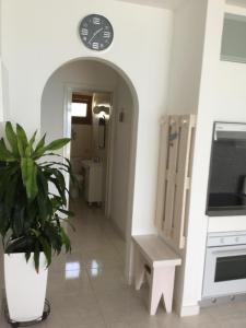 a hallway with a clock on the wall and a plant at Pissouri Beach Front Apartments in Pissouri