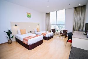 a hotel room with two beds and a desk at Kingston Hotel 15 - Tower Regency, Ipoh in Ipoh