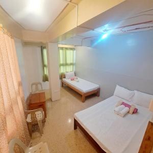 a small room with two beds and a table at Baguio Tourist Cabin in Baguio