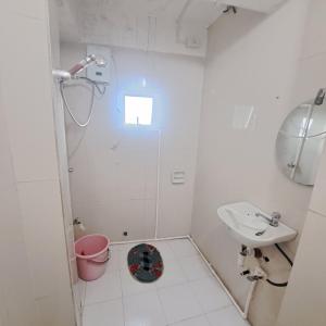 a white bathroom with a shower and a sink at Baguio Tourist Cabin in Baguio