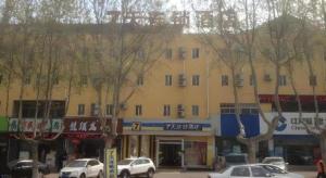 un grande edificio giallo con le auto parcheggiate di fronte di 7 Days Inn Yantai Dahaiyang Raod Railway Station a Yantai