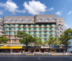 长沙IU Hotel Changsha Yuanjialing Metro Station 2nd Hospital of Xiangya的前方树木林立的街道上一座大型建筑