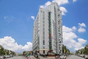 a tall white building with cars parked in a parking lot at GreenTree Inn JinDeZhen People Square Taoxichuan Wenchuang Street in Jingdezhen
