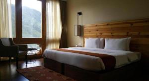 um quarto de hotel com uma cama grande e uma janela em The Pema by Realm em Thimphu