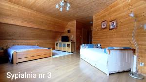 a bedroom with two beds and a wooden wall at Wiślany Raj in Wisła