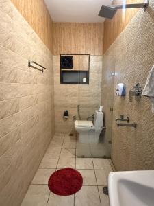 a bathroom with a toilet and a red rug at HolidayVilla - 1st Japanese Pod, Rooms & Suites - Green Avenue Amritsar in Amritsar