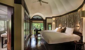 a bedroom with a large white bed and a desk at Rayavadee - Deluxe Pavilion in Railay Beach