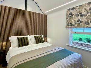 Boutique Cottage by Bishop's Stortford train station, easy to Stansted Airport & Parking في بيشوبس ستورتفورد: غرفة نوم بسرير كبير ونافذة