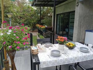 a table with plates and bowls of fruit and flowers at Baan suan khun Pen Chiangmai in Ban Luam