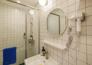 ein weiß gefliestes Badezimmer mit Waschbecken und Spiegel in der Unterkunft Blue Mansion Seoul in Seoul + 79 Fotos