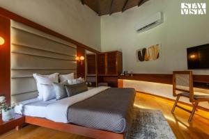 una camera da letto con un letto, una scrivania e una televisione di StayVista's Lush Villa - Rustic-Meets-Modern Interiors, Pool, Jacuzzi & Indoor activities a Wādhiware