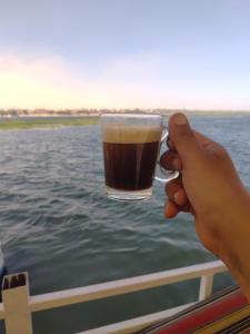 a person holding a glass of beer on a boat at Nile SE Felucca nile cruise private tour in Naj‘ al ‘Amrāb +1 photo