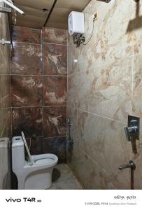 a bathroom with a toilet and a tiled wall at Shree Ram Palace in Ayodhya +6 photos
