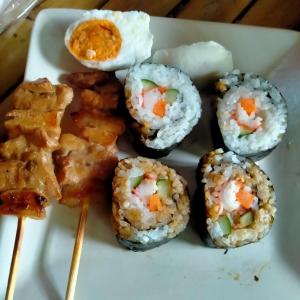 清迈Ouychai home stay resort的盘子里放着一盘寿司和筷子。