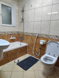 a bathroom with a toilet and a sink and a shower at Delightful Private Rooms with Garden View in Sharjah