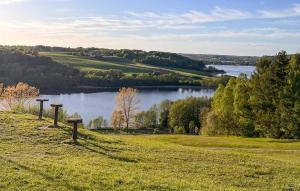 Un campo con vista a un lago y una colina con árboles. en Amazing Home In Prokowo With Wifi, en Prokowo 7 fotos más