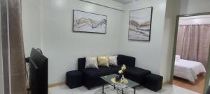 a living room with a black couch and a mirror at camella northpoint condominium close to airport,sm lanang,abreeza mall,spmc,dmsf,usep in Davao City