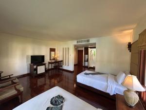 a hotel room with a bed and a television at Teak Garden Resort, Chiang Rai in Chiang Rai