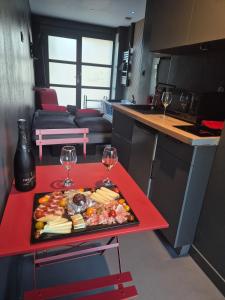 Studio Balnéo Bord de mer Fouras - 800m de la plage في فورا: طاولة حمراء عليها صينية طعام وكؤوس نبيذ