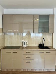 a kitchen with white cabinets and a sink at Apartman Nota in Vinkovci +8 photos