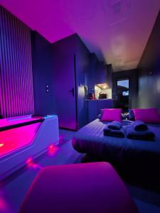 Studio Balnéo Bord de mer Fouras - 800m de la plage في فورا: غرفة نوم مع إضاءة وردية وسريرين فيها