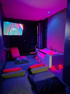 Studio Balnéo Bord de mer Fouras - 800m de la plage في فورا: غرفة بها سريران وجهاز تلفزيون بإضاءة وردية