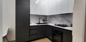 a kitchen with black and white cabinets and a stove at CozyNest Apartment In Yerevan, Center in Yerevan