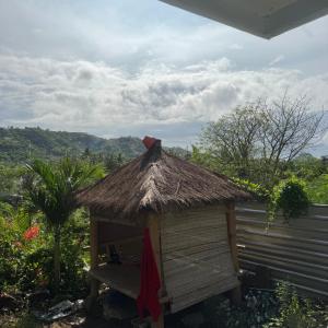 Una pequeña choza con techo de paja y un banco. en Sunrise Bukit Asam Home Stay, en Kuta Lombok