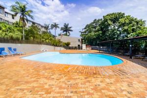 巴利托Chaka's Rock Beach Chalet 38的庭院里的大型游泳池,设有椅子和树木