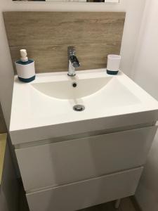 a white bathroom sink with two cups on it at Studio à la vallée heureuse in Sorède