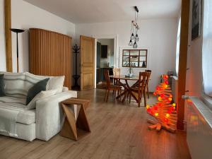 Petite maison SOUS LE TILLEUL في ستشيلتيغهيم: غرفة معيشة مع أريكة وطاولة مع شجرة عيد الميلاد